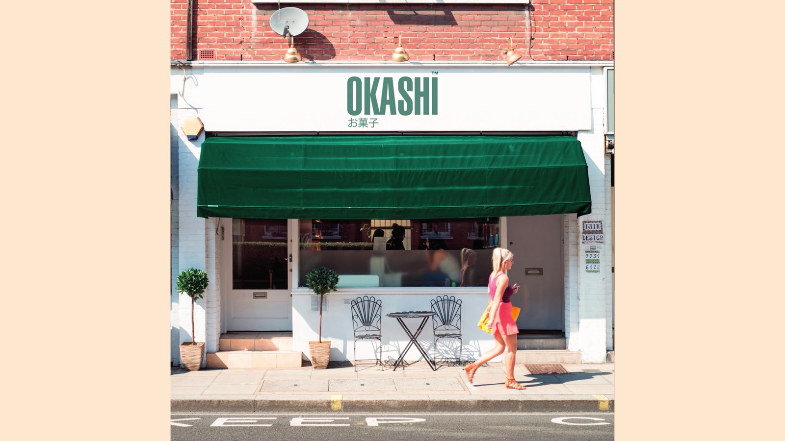 Okashi shopfront on a London street, green awning and wordmark over a white facade