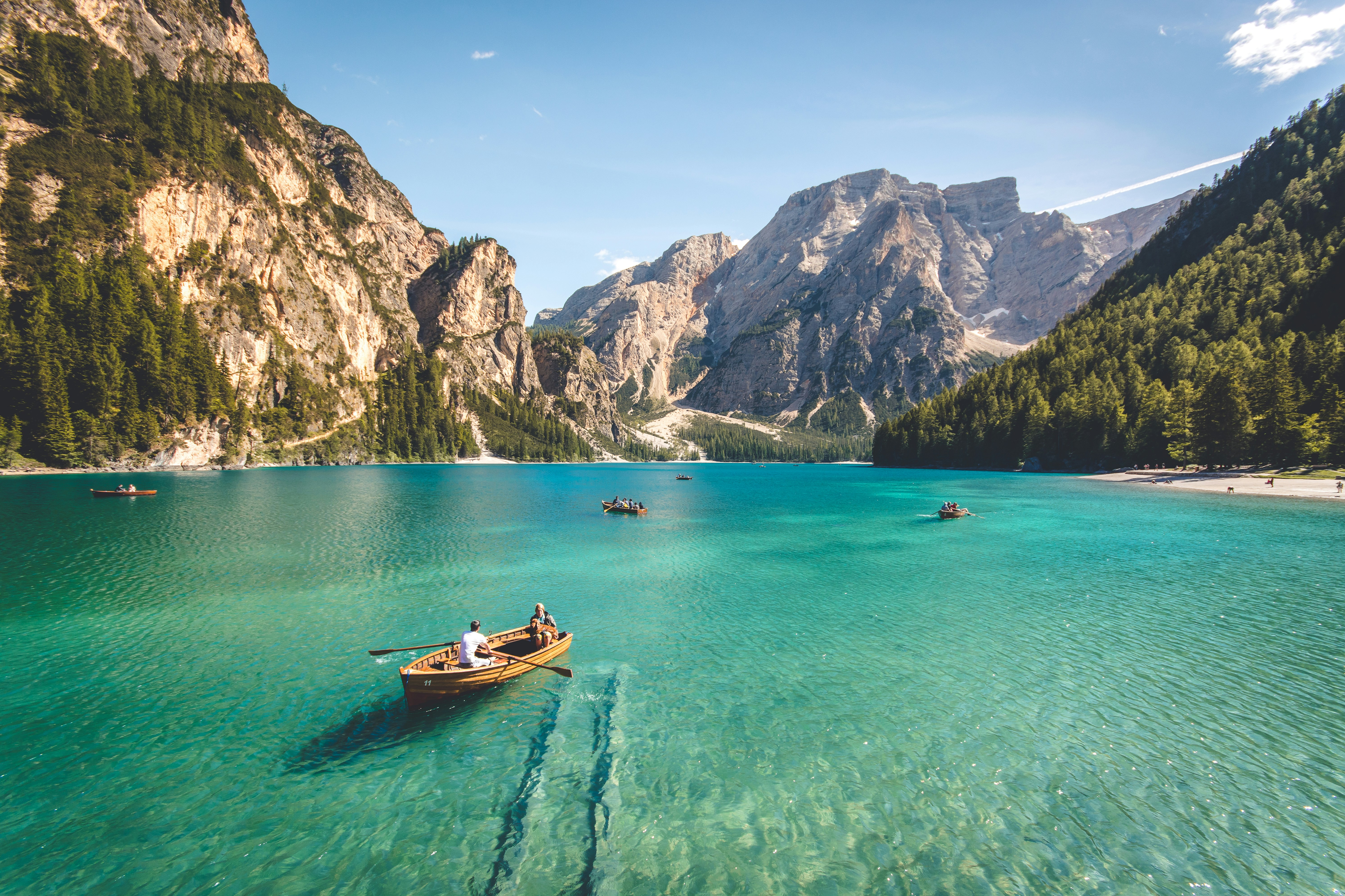 Wooden rowboats on a turquoise alpine lake, the kind of remote destination booked through Quintessentially Travel